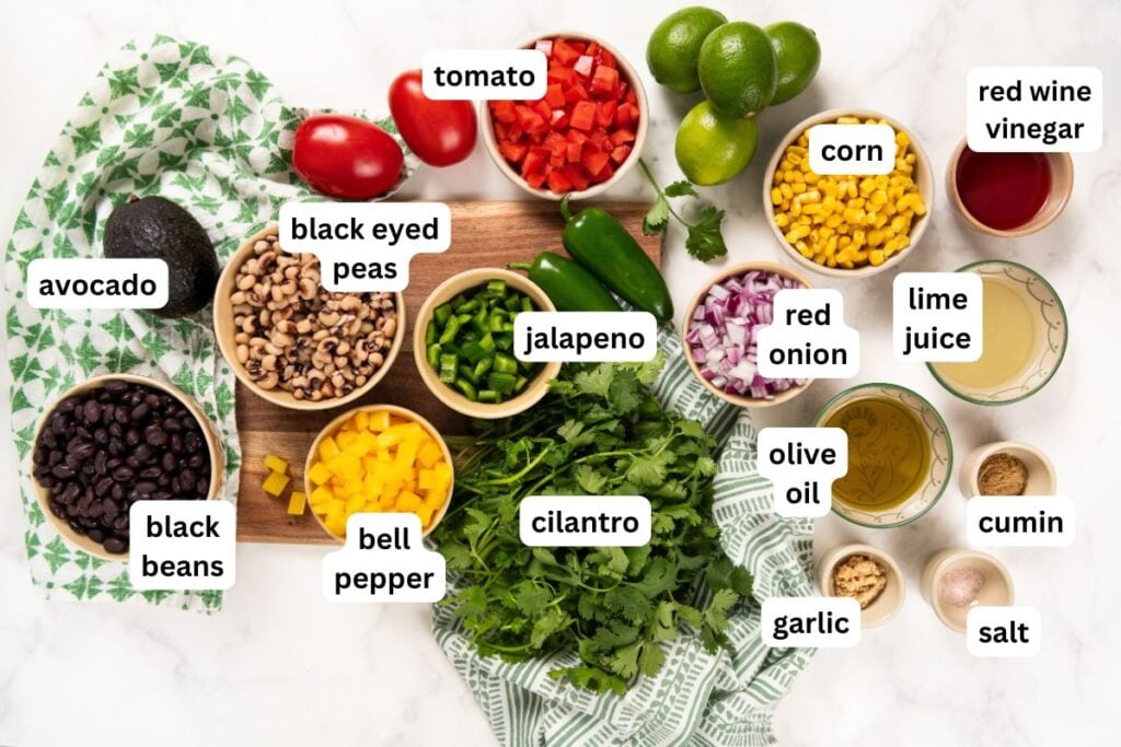 Best made in advance, Cowboy Caviar dip is fresh, colorful, and full of black beans, corn, and crunchy veggies in a tangy lime dressing. Various fresh ingredients for cowboy caviar recipe, each labeled: avocado, black beans, black eyed peas, tomato, jalapeno, cilantro, bell pepper, corn, red onion, lime, red wine vinegar, lime juice, olive oil, cumin, garlic, salt.