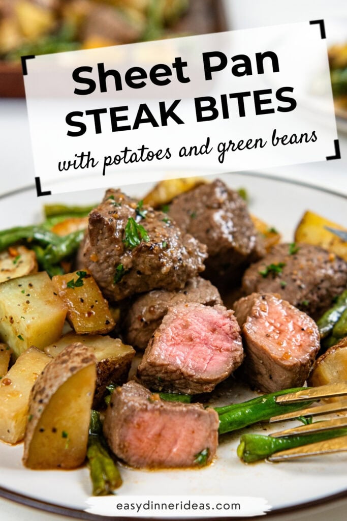 Plate of steak bites, roasted potatoes, and green beans with a text overlay reading Sheet Pan Steak Bites with potatoes and green beans. Food appears fresh, garnished with herbs, and easy dinner ideas website noted.