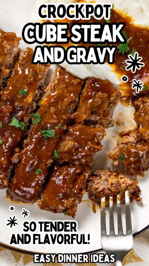 Sliced crockpot cube steak covered in gravy is served with mashed potatoes on a white plate. The image includes text: Crockpot Cube Steak and Gravy, So tender and flavorful! Easy dinner ideas. A fork rests near the steak.