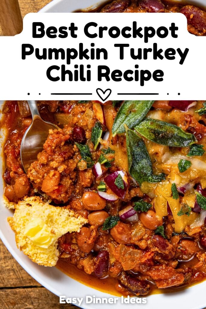A bowl of pumpkin turkey chili topped with cheese, herbs, and red onions, served with a spoon and a piece of cornbread with butter.