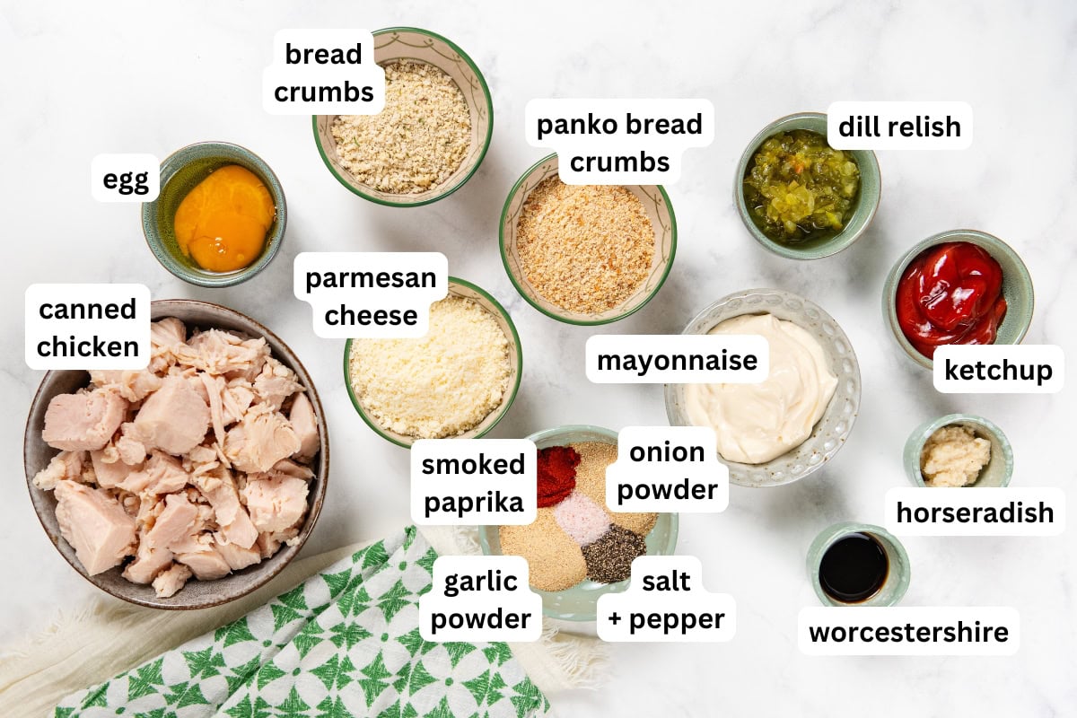 This Chicken Patty Sandwich turns two cans of chicken into a quick and easy dinner for six! Served with a tangy sauce and all the toppings. Bowls containing canned chicken, egg, bread crumbs, parmesan, panko, dill relish, mayonnaise, ketchup, horseradish, Worcestershire sauce, smoked paprika, onion powder, garlic powder, and salt and pepper are labeled.