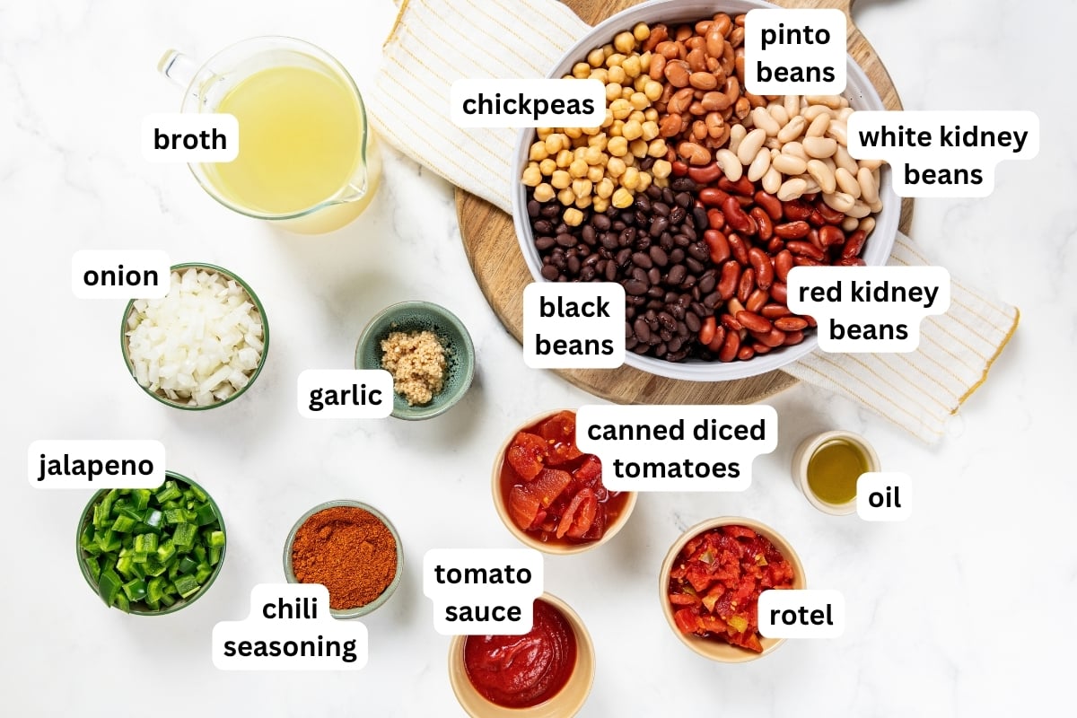 So thick and hearty, this 5 Bean Chili recipe is made in just one-pot with canned beans and a few simple pantry staples. Ready in 30 minutes! Ingredients like canned beans in a large bowl, broth, chopped onion, chopped jalapeno, minced garlic, chili seasoning, diced tomatoes, tomato sauce, Rotel, and oil, each labeled with its name.