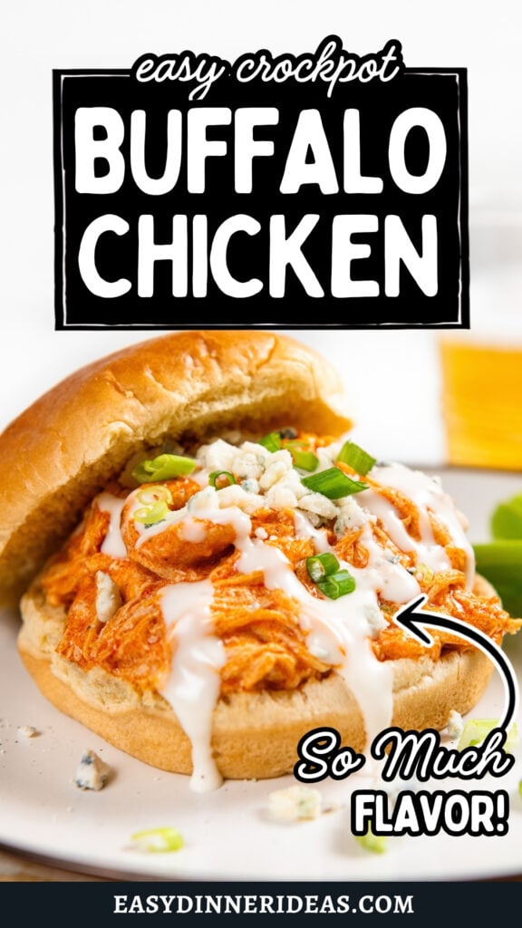 A crockpot buffalo chicken sandwich topped with ranch, blue cheese crumbles, and green onions on a white plate.