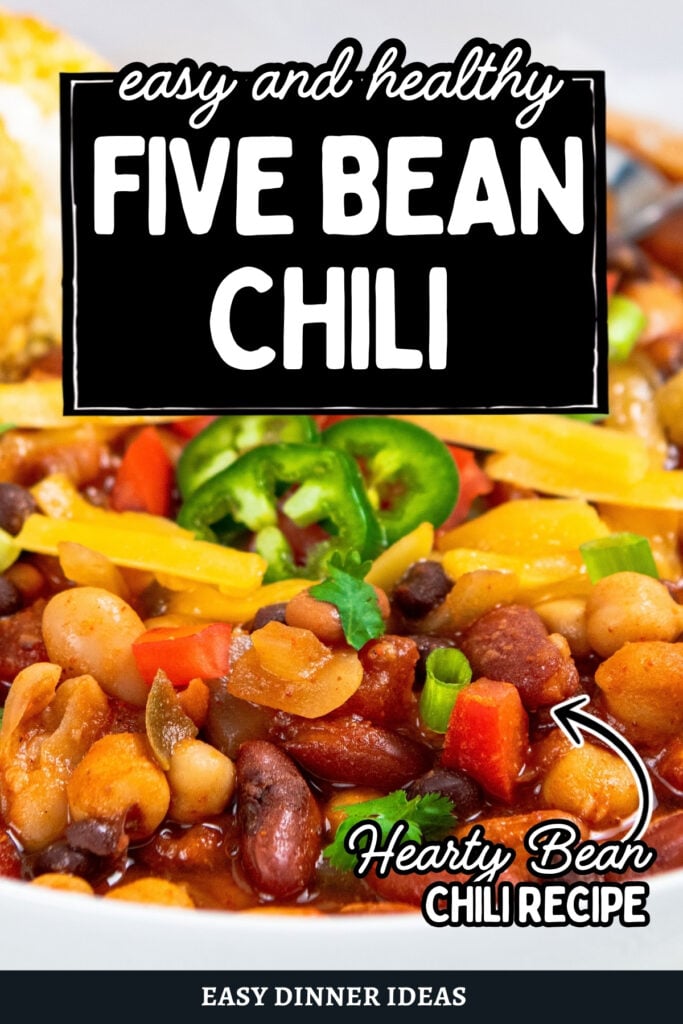 A bowl of 5 bean chili topped with cheese, jalapeño slices, and chopped green onions.